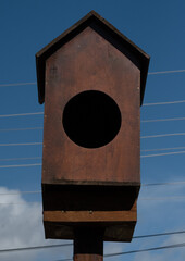 Vertical closeup shot of a wooden birdhouse against a blue sky