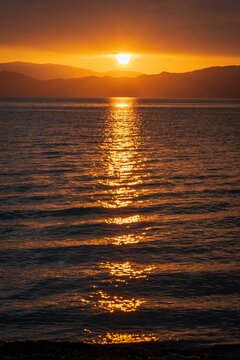 Vertical shot of a beautiful tranquil sea and a reflection of a golden sunset in it