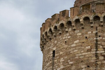 Closeup shot of a part of an old stone tower with blue sky in the background
