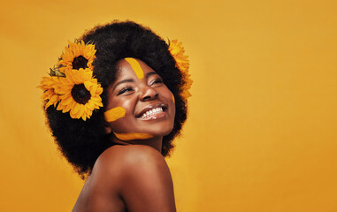 Beautiful black woman, sunflowers in hair and make up on face in studio for cosmetics, afro care...