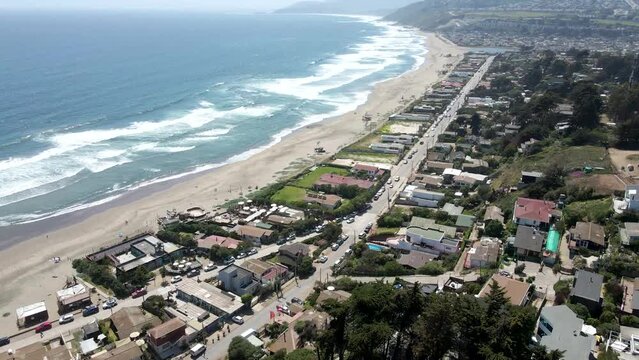 Bird's eye view of a city on the beach against ocean waves on a sunny day