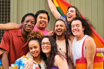 A group of people are posing for a picture with a rainbow flag at Pride Day. Scene is happy and...