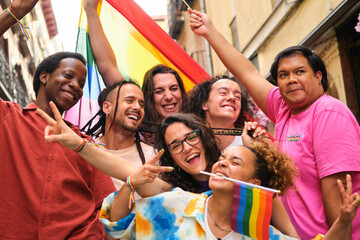 Happy group of LGBTQ people smiling and laughing with rainbow flags celebrating International Pride...