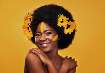 Black woman, sunflowers in hair and make up on face in studio portrait for cosmetics, afro care and...
