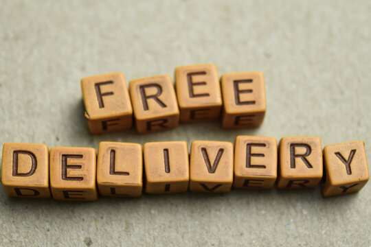 Concept of Free Delivery message written on wooden blocks. Cross processed image on Wooden Background