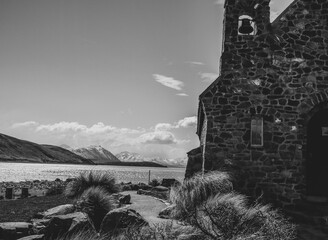 Grayscale closeup of Good Shepherd church view tussock grass around and sky background