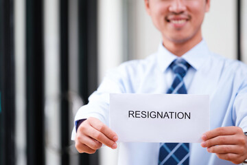 Smiling man displays resignation letter, suggesting a hopeful new beginning.