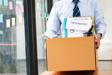 Man leaves office holding a box with personal items, including resignation letter.
