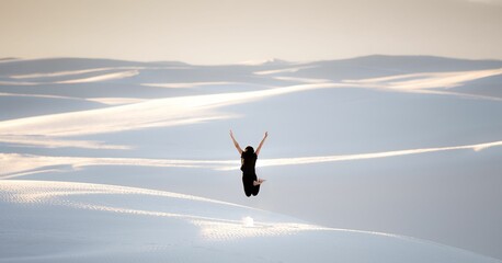 Female in black clothing jumping with happiness at White Sands National Park