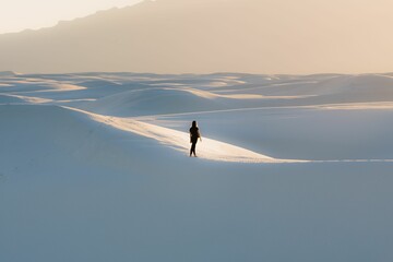 Female in black clothing walking on a dune at White Sands National Park