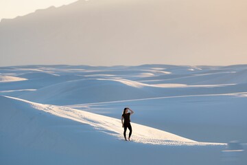 Female in black clothing with one hand on her forehead at White Sands National Park