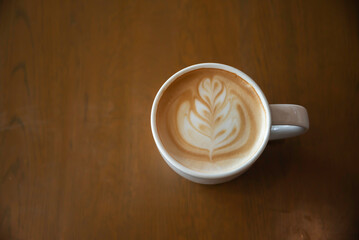 Hot latte art coffee cup on wooden table