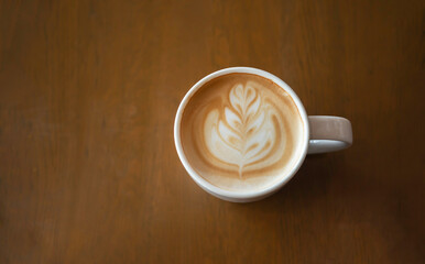 Hot latte art coffee cup on wooden table
