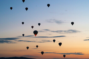 Hot air balloons rising over the landscape of the Red Valley, Rose Valley before sunrise, close to...