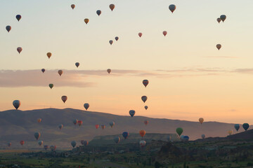 Dozens of colorful hot air balloons over the landscape of the Red Valley, Rose Valley right before sunrise, close to Goreme, Cavusin, Cappadocia, Turkey