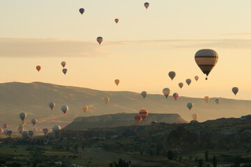 Colorful hot air balloons over the landscape of the Red Valley, Rose Valley about to land next to...