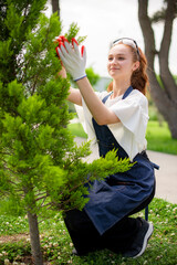 Side view of girl with red hair growing plants, holding branch by hands. Concept of taking care of plants.