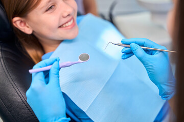 Smiling teenage girl sits in the dentists chair