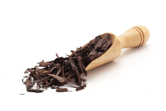 Front view of a wooden scoop filled with Organic Alkanet or Ratan Jot (Alkanna tinctoria) roots. Isolated on a white background.