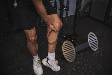 An anonymous suffering from leg cramps while at the gym. Excruciating pain from tight calf muscles.