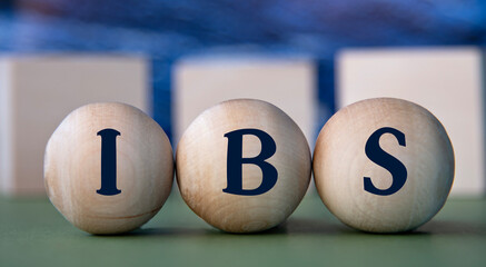 IBS - acronym on wooden balls on the background of wooden large cubes