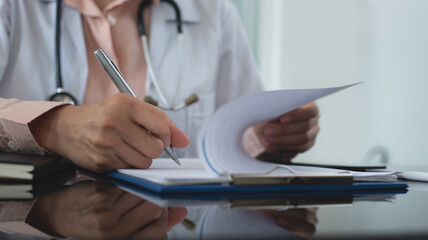 Asian woman doctor working and taking note information of patient on medical document on clipboard...