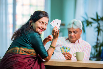 Mature Indian couple enjoying while playing cards together at home
