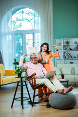 Happy old Indian asian senior grandparents couple waving hand making online video call enjoying...