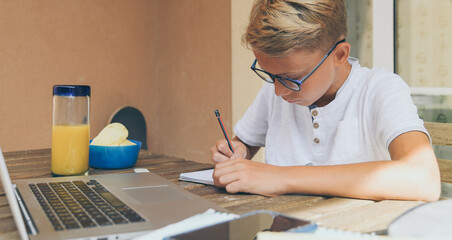 Student doing homework. Boy writing, drawing sitting at the table. School, youth, education concept.