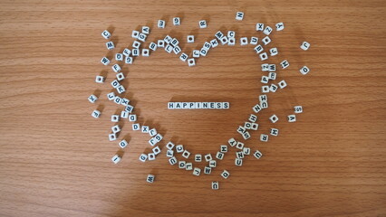 Happiness - words from alphabet white beads blocks with letters in heart, random letters around,...