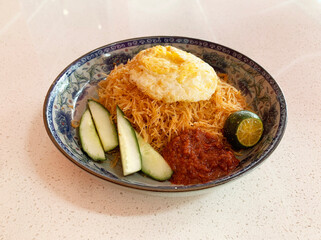 traditional peranakan wok stir fried nonya mee siam noodle spicy chilli shrimp goreng with egg lime sambal cucumber in plate on vintage table asian cafe hotel luxury halal food restaurant banquet menu