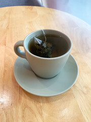 hot drink milk tea leaf bag, milo , kopi coffee mocha with milk in traditional cup and tea spoon and small plate on wood table color vegan healthy restaurant beverage cafe halal food menu