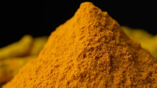 Macro shot of turmeric powder slowly swirling on black background