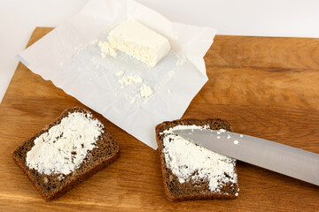 Cheese is spread on slices of black bread.