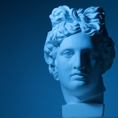 
sculpture head face of the ancient Greek god Apollo on a dark blue background in a ray of light...