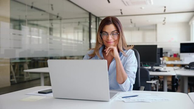 Happy busy mature business woman employee in office using laptop at work, smiling professional middle aged female company manager working looking at computer at workplace.