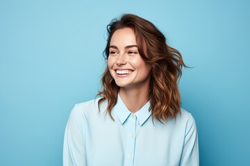 A woman with brown hair and a blue shirt is smiling - Powered by Adobe