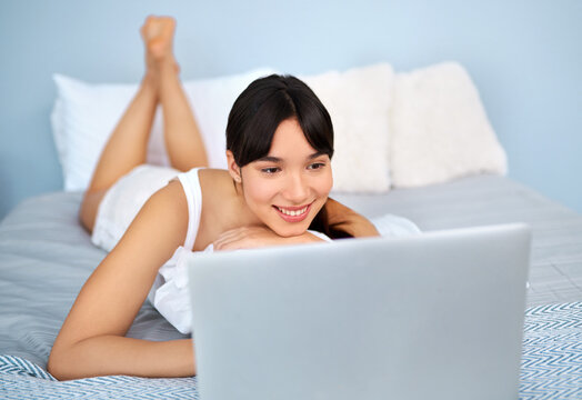 Woman, laptop and smile with lying on bed for relax or streaming on internet with video. Bedroom, social media and technology with subscription for movie in pyjamas on website for enjoyment in house