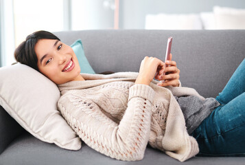 Asian woman, home and smile on sofa with smartphone, text and messages with dating app and social...
