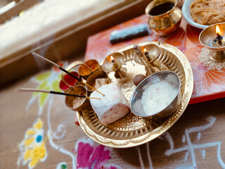 Diya light flame with rangoli decoration and aarti dish closeup