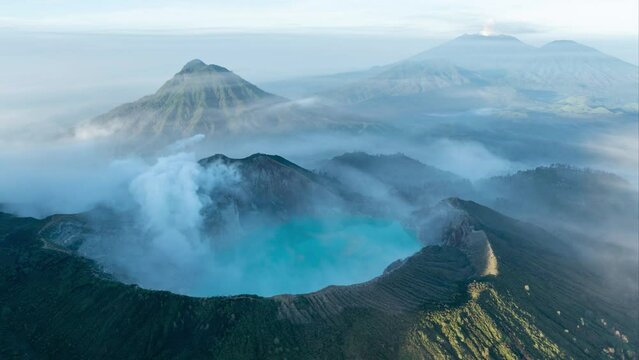 Rotating aerial time lapse of smoking active Ijen volcano and caldera with surrounding landscape during sunrise on East-Java, Indonesia
