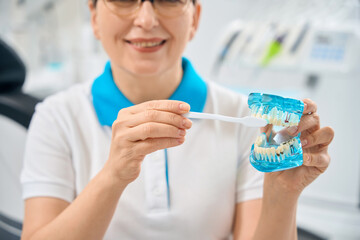 Woman dental hygienist showing the right way to brush teeth