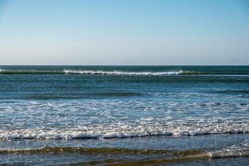 Detail of the waves of the Atlantic sea beating on the golden sand beach during the summer holidays in the province of Huelva, Spain.
