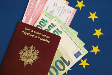 French passport of European Union and airlines tickets with money on blue flag background close up....
