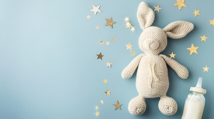 Child toy knitted rabbit with milk bottle,  knitted bunny toy milk bottle and gold stars on isolated pastel blue background with copy space