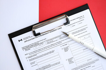 Application for permanent resident card on table with pen close up