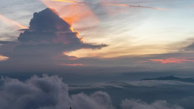 Time lapse of thunder cloud developing over mountain landscape at sunset with lightning and red and orange colours at Bali, Indonesia