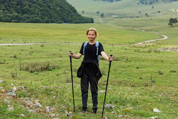 Photo of young beautiful hiker girl going to mountains travel with backpack and trekking pole, enjoying local scenery. Concept of travelling, hiking. high quality photo