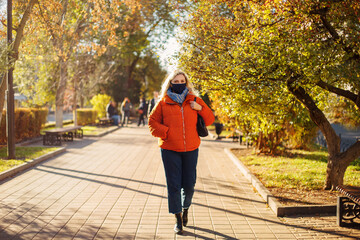 Female in mask walking in autumn park