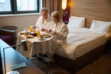 Caucasian couple having breakfast and looking at each other on bed at table